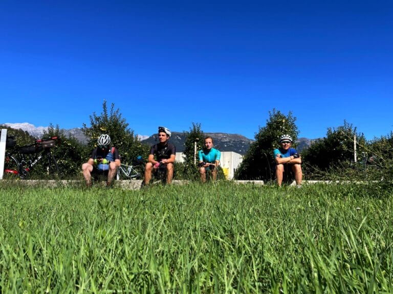Pauze met geplukte appel uit appelgaard in Italiaanse Alpen Foto in laag perspectief boven het gras zitten fietsers in de zon een appel te eten voor een appelgaard