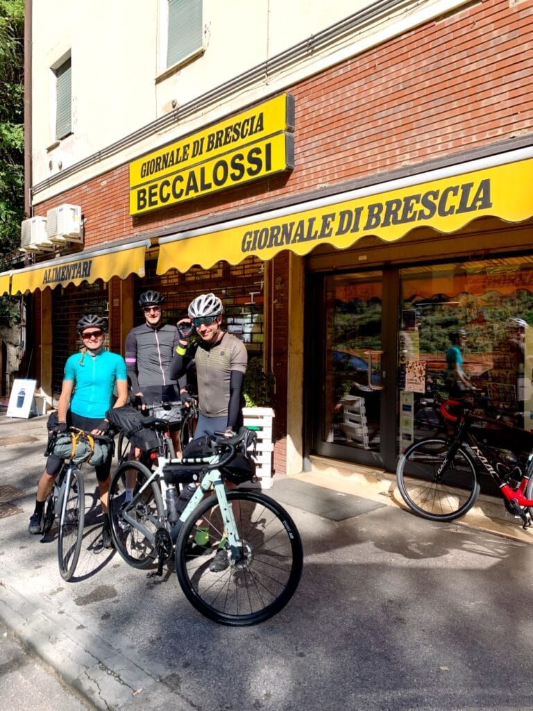 Italiaanse Alpen Giornale di Brescia groepsfoto Fietsers in regio Brescia voor een Tabaccheria aan de start van een fietstocht in de Italiaanse Alpen