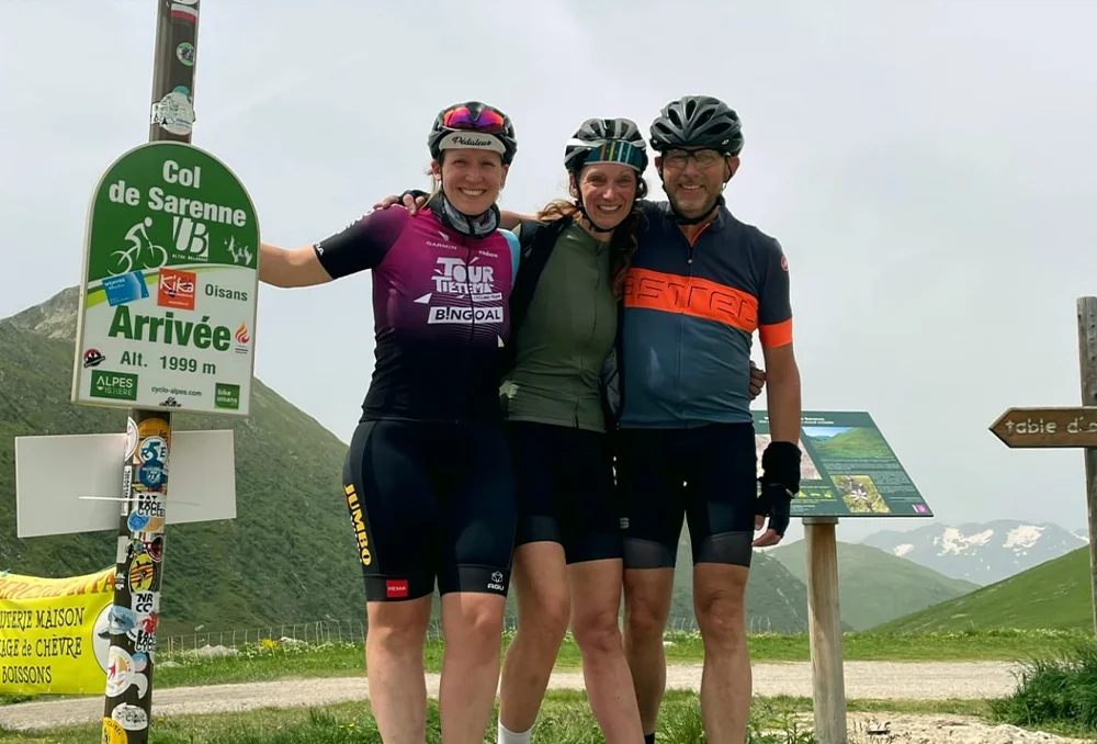 Col du Sarenne groepsfoto naast colbord met drie wielrenners