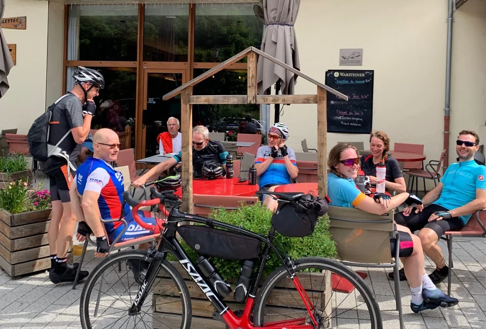 Terras met wielrenners en een fiets in La Meije tijdens een pauze. Franse Alpen Rudi Rides