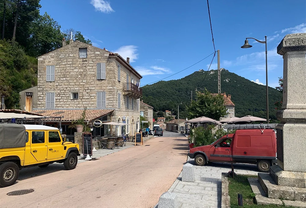 Klein verlaten dorp met enkele auto's in het binnenland van Corsica
