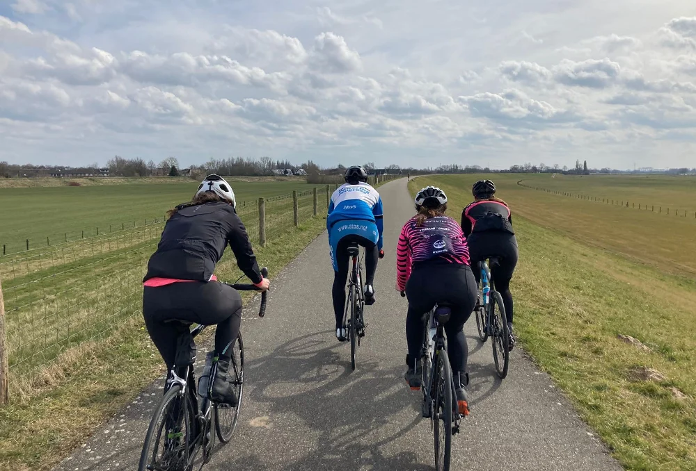 Wielrenners op de dijk vanaf de achterkant in het voorjaar in Nederland