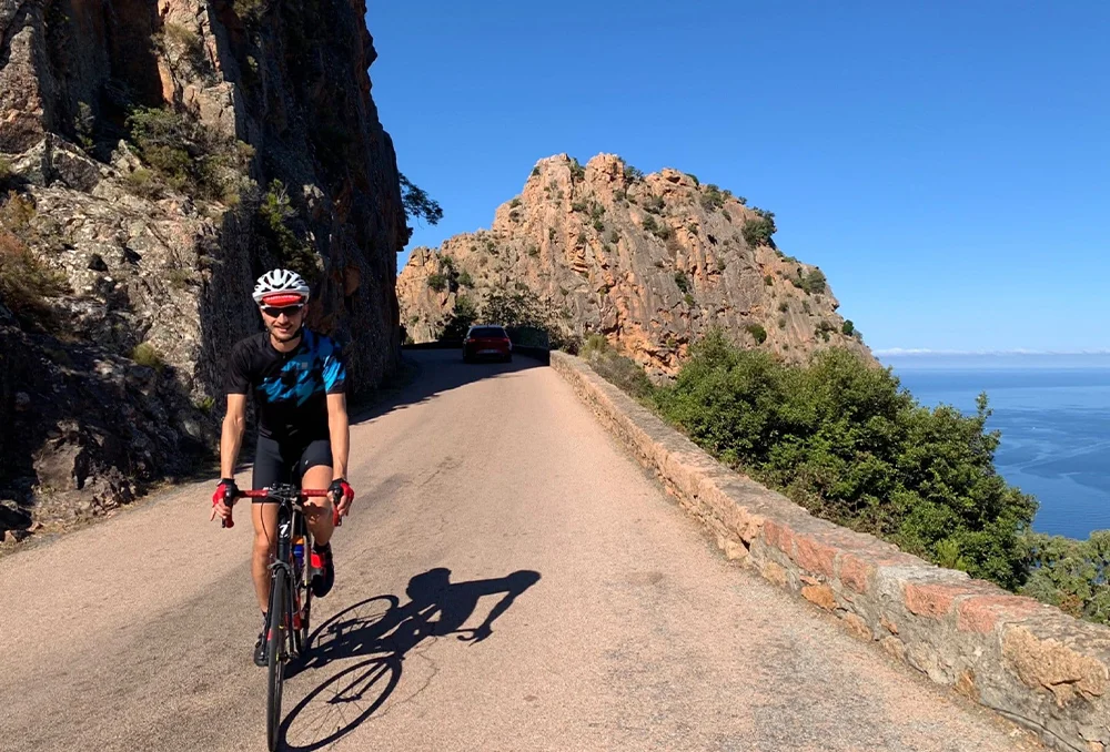Een fietser van Rudi Rides fietst langs Calanches de Piana op Corsica